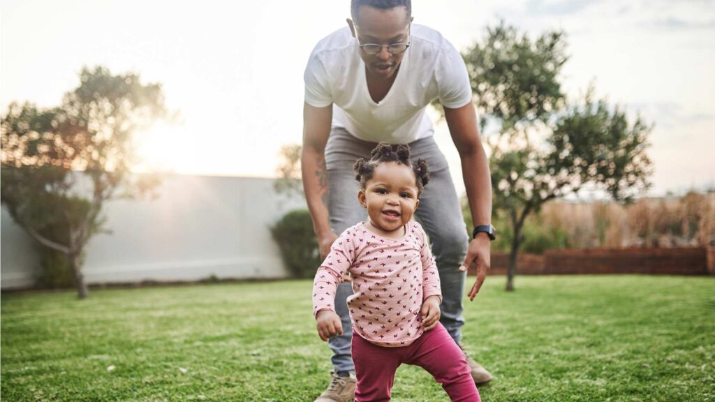 Dad playing with baby daughter in back yard