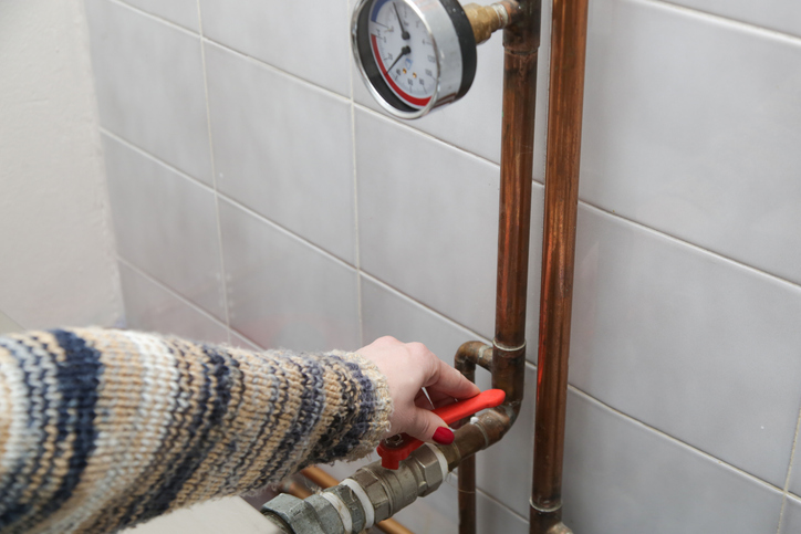 A part of central heating system. Woman hand adjusting valve for home heating.