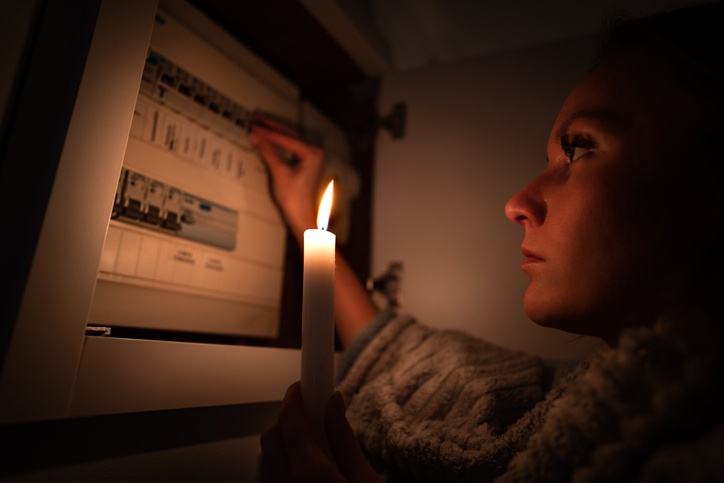 Woman checking fuse box at home during power outage or blackout.