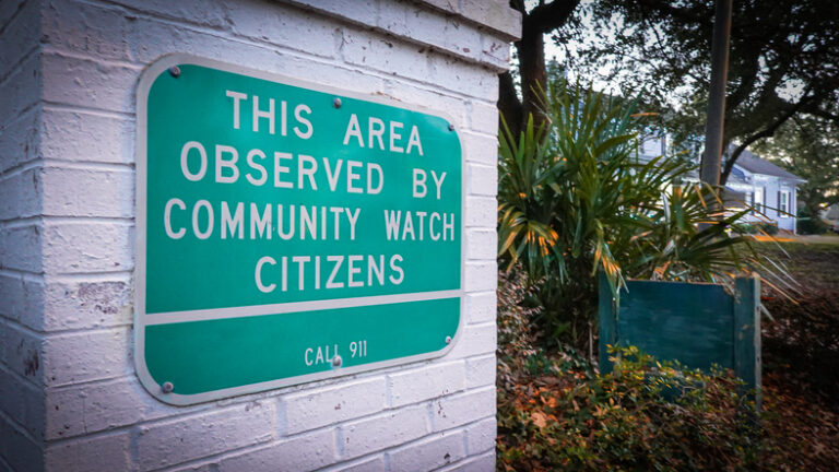 A neighborhood community watch sign warns potential intruders.