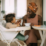 Young mother feeding her baby boy in the living room at home