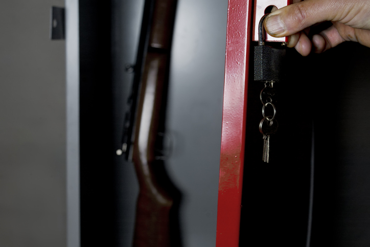 Human hand opening a metal safe with a gun inside.
