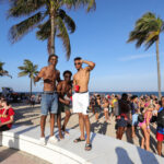 Three young men strike a pose on the beach.