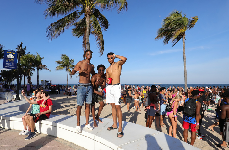 Three young men strike a pose on the beach.
